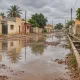 Illustration générée par IA : rue inondée au Sénégal, eaux stagnantes et caniveau après de fortes pluies.